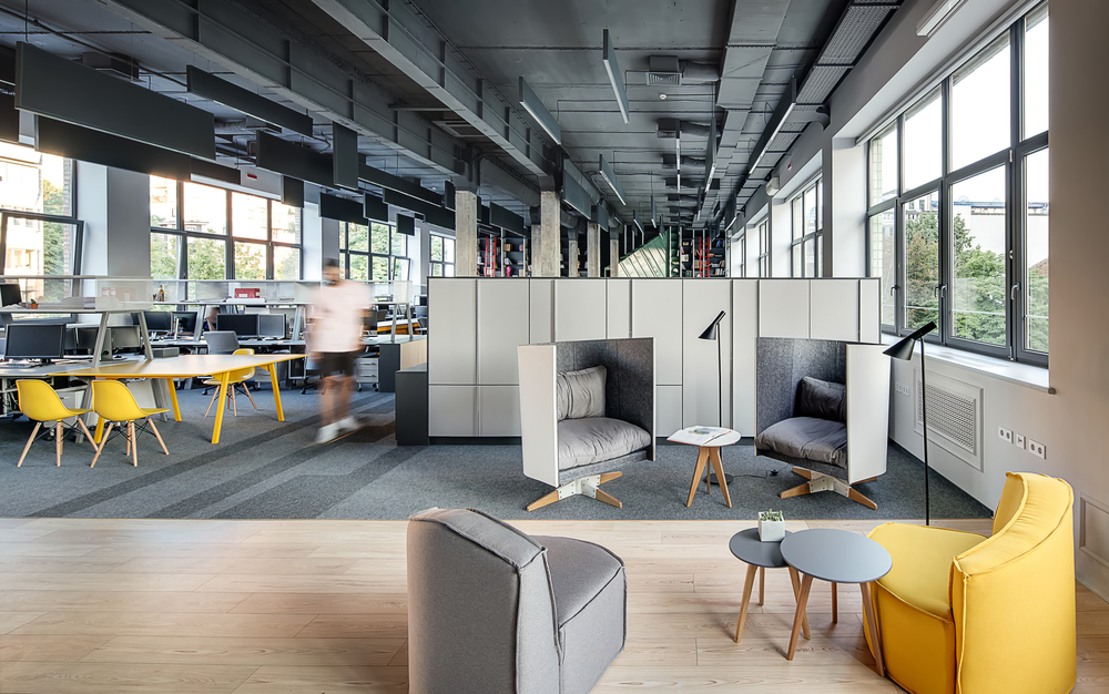 A harmonious blend of functional workstations, shelves, and lockers, alongside cozy armchairs, round tables, and private pods, catering to both collaboration and solitude.